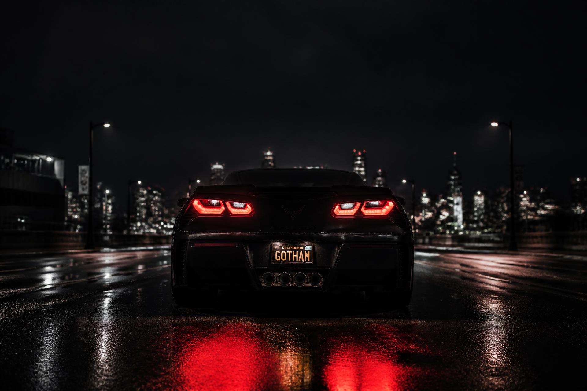 Black C7 Corvette from the rear on a wet city street at night